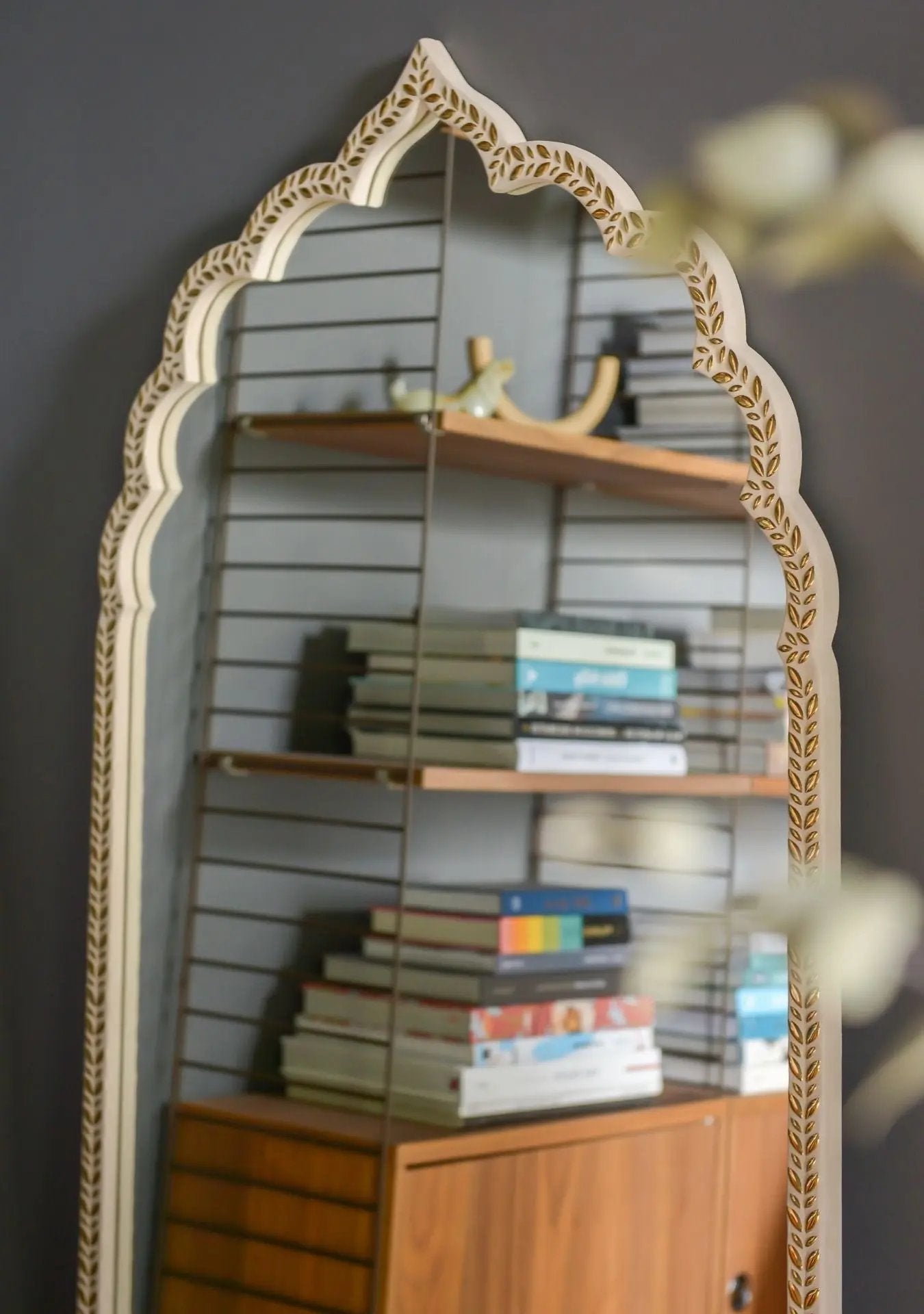 Handmade arched mirror with golden ceramic stones creating a warm, luminous effect.