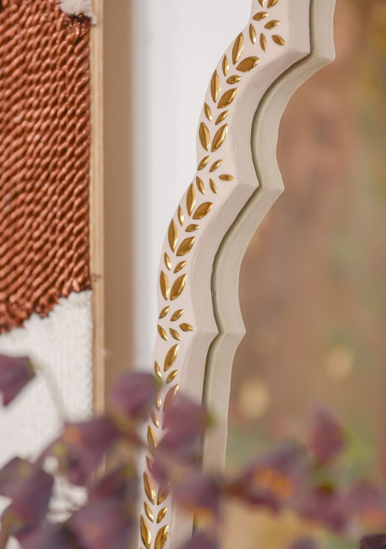 Close-up of handcrafted mirror with golden mosaic leaf pattern and soft, organic curves – Pure Reflection.