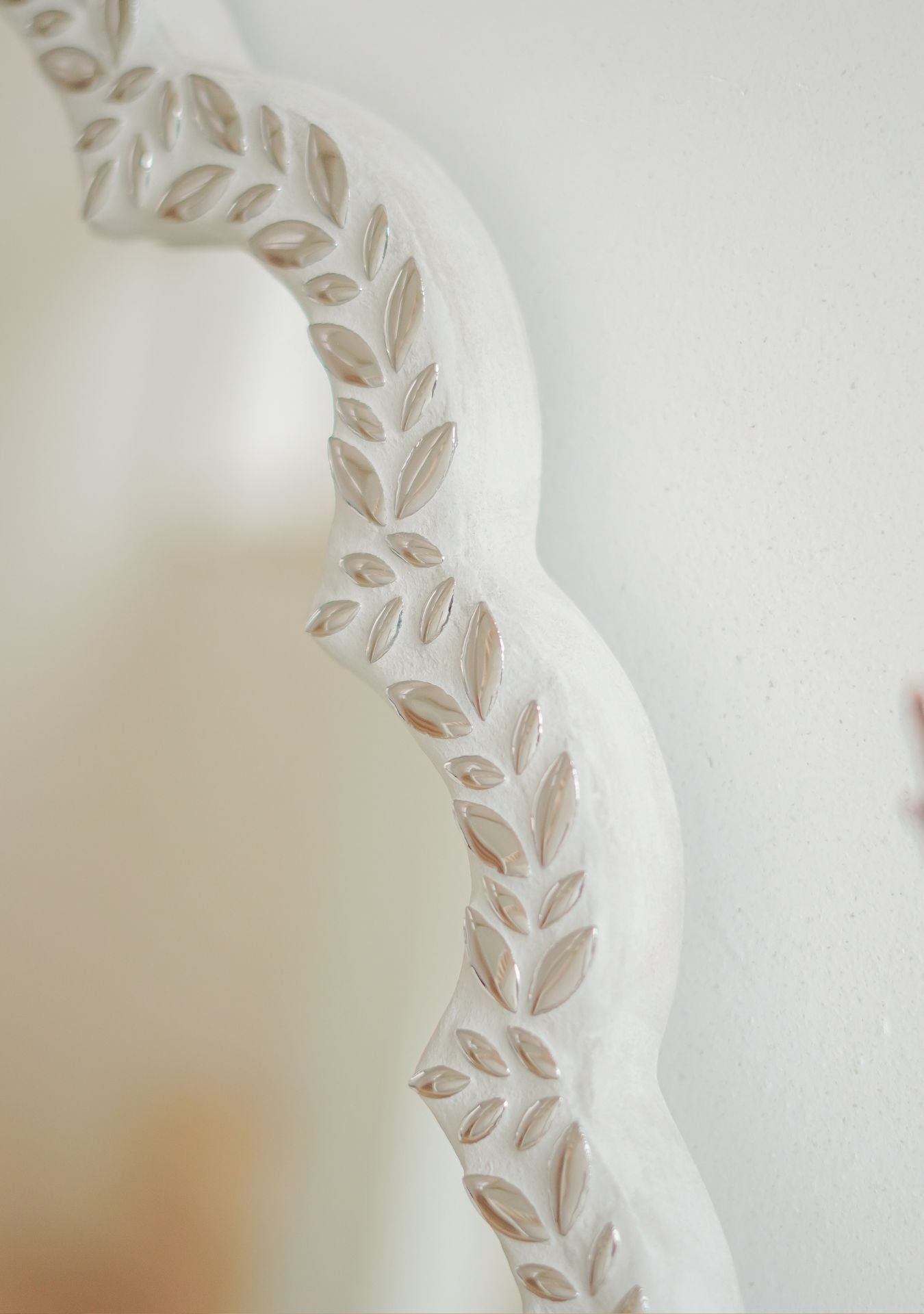 Close-up of handcrafted mirror with silver mosaic leaf pattern reflecting a soft neutral interior – Pure Reflection.