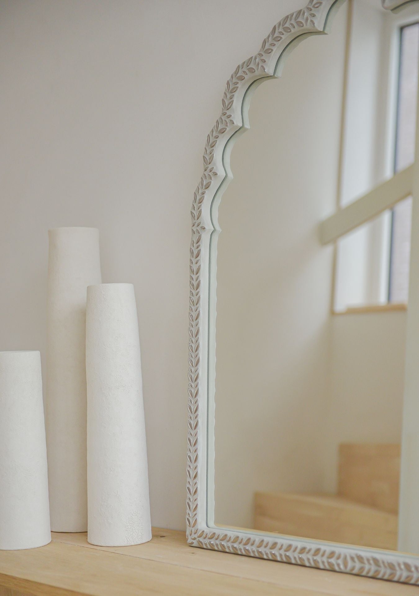 Handcrafted mirror with silver mosaic leaf frame in oriental shape, styled on a wooden shelf with minimalist ceramic vases – Pure Reflection.