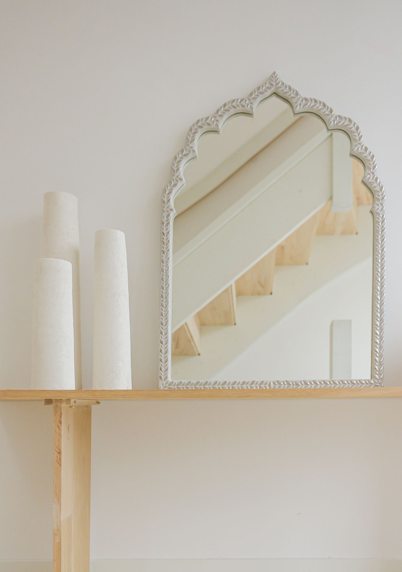 Handcrafted oriental mirror with silver mosaic frame on a minimal wooden shelf, reflecting soft neutral tones – Pure Reflection.