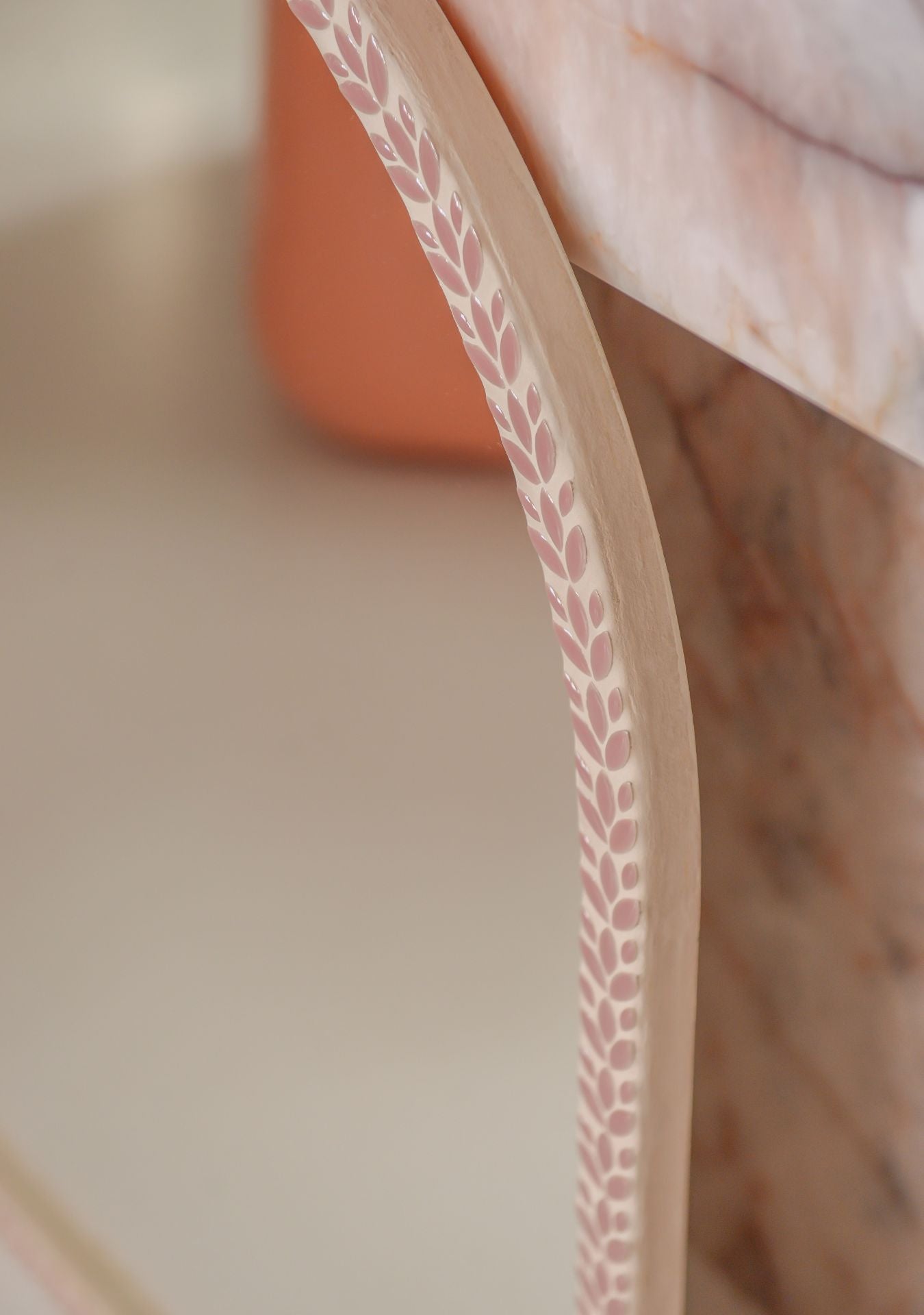 Close-up of a handmade pink mosaic mirror by Pure Reflection, highlighting the curved arched shape and intricate leaf-patterned mosaic frame detail.