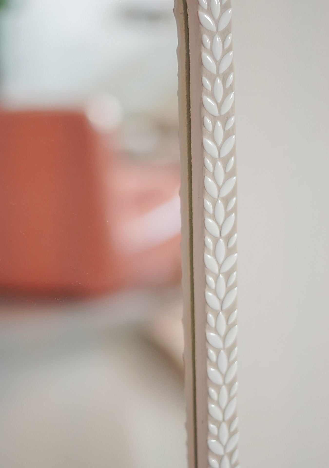 Detailed view of white ceramic leaf pattern and grout texture on handmade designer mirror.