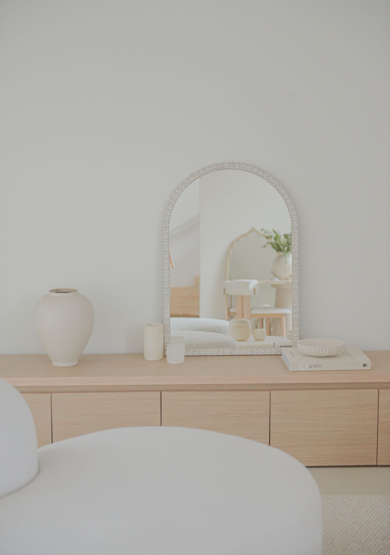 Handmade white mosaic mirror by Pure Reflection styled in a serene, minimalist interior with natural light, soft neutral tones, and a light wooden cabinet for a calm and elegant atmosphere.