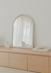 Handmade arched mosaic mirror by Pure Reflection styled in a bright, minimal interior with neutral tones, placed on a light wooden cabinet with soft natural light and serene decor.