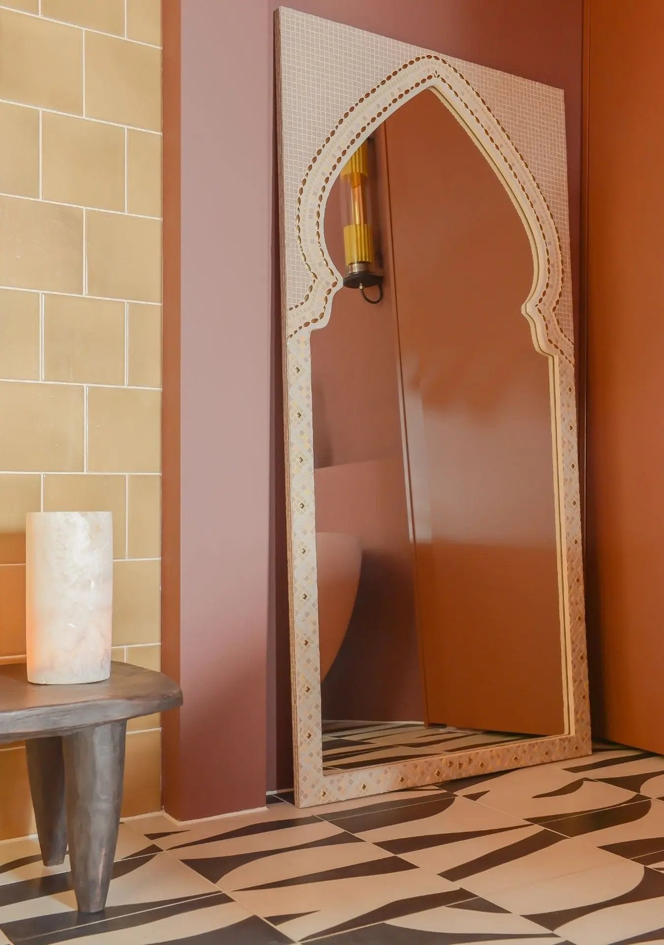 Large arched mosaic mirror creating a calming atmosphere in a soft-toned interior.